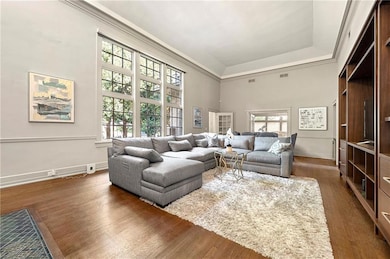 Living area featuring wood finished floors, a towering ceiling, a tray ceiling, and crown molding