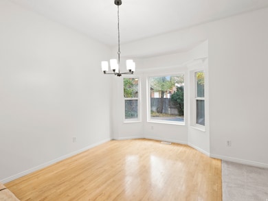 Unfurnished room with light wood-type flooring and a chandelier