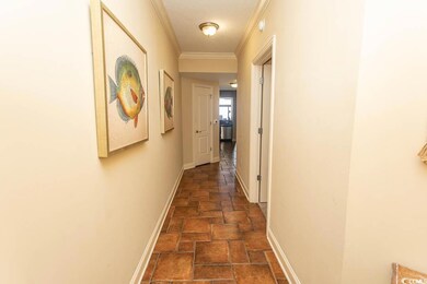 Hall featuring stone tile flooring, baseboards, and crown molding