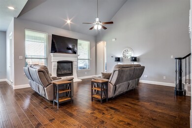 Living area featuring plenty of natural light, a glass covered fireplace, dark wood finished floors, and high vaulted ceiling