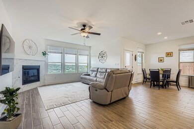 Living area with a tile fireplace, light wood-type flooring, a ceiling fan, and recessed lighting