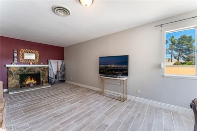 Unfurnished living room featuring a stone fireplac