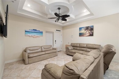 Tiled living room with a tray ceiling and ceiling fan