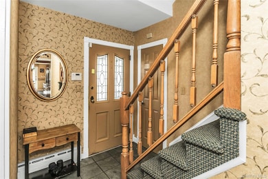 Entryway featuring wallpapered walls, stairway, a baseboard radiator, and tile patterned floors