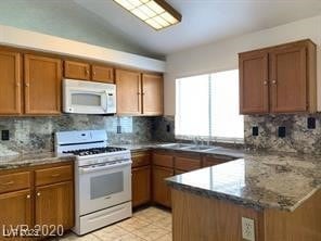 Kitchen with white appliances, brown cabinets, tas