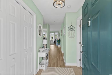 Entryway with baseboards, wood finished floors, and a chandelier