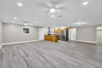 Unfurnished living room with ceiling fan, ornamental molding, recessed lighting, and light wood finished floors