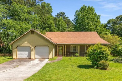 View of front of home with driveway, an attached garage, a front yard, and a porch