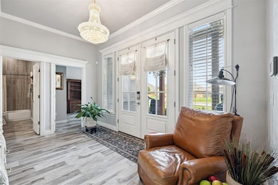 Sitting room featuring a chandelier, ornamental molding, light wood-style flooring, and baseboards