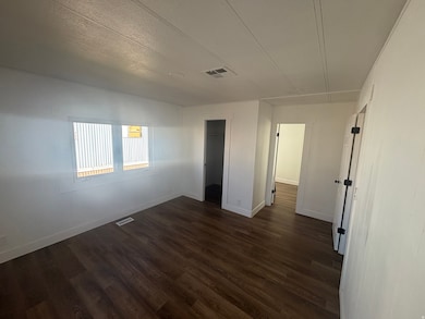 Spare room featuring dark wood-type flooring and a textured ceiling