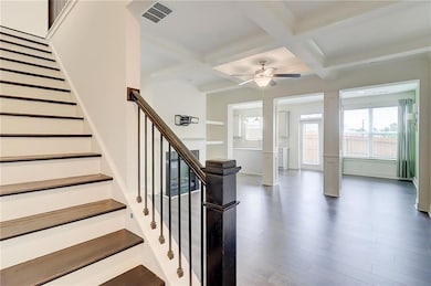 Stairway featuring a ceiling fan, coffered ceiling, beam ceiling, wood finished floors, and ornate columns