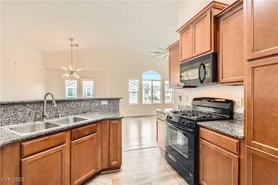 Kitchen featuring black appliances, a sink, vaulte