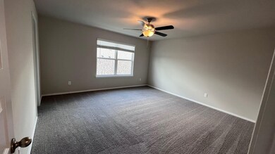 Carpeted empty room with baseboards and a ceiling fan