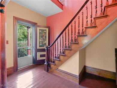 Entrance foyer featuring hardwood / wood-style floors, stairway, and wallpapered walls