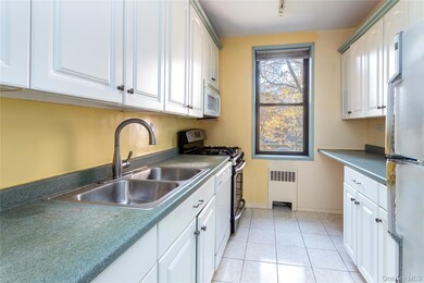 Kitchen with dark countertops, white appliances, and white cabinetry