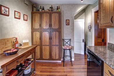 Kitchen featuring dark hardwood / wood-style floors, dark stone countertops, and black dishwasher