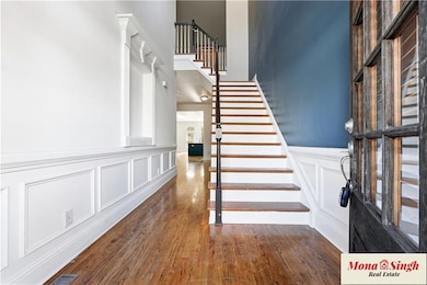 Staircase featuring wood finished floors, a decorative wall, and wainscoting