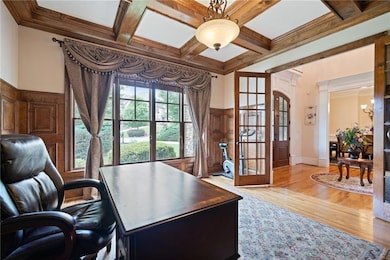Home office with coffered ceiling, beamed ceiling, a chandelier, light wood finished floors, and ornamental molding