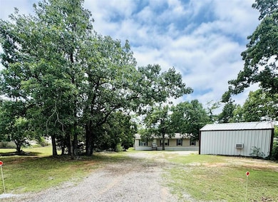 View of grassy yard with gravel driveway and an outbuilding