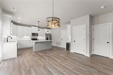 Kitchen with stainless steel appliances, wine cooler, a center island, a chandelier, and light countertops