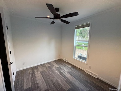 Spare room with dark wood finished floors, crown molding, a textured ceiling, and ceiling fan