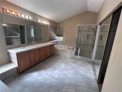 Full bath featuring a bath, vaulted ceiling, double vanity, and a stall shower