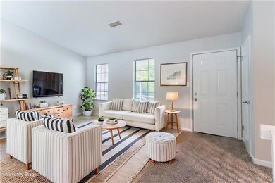 Living area featuring vaulted ceiling, baseboards, and carpet flooring