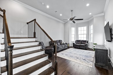 Living area with crown molding, dark wood finished floors, recessed lighting, stairway, and ceiling fan