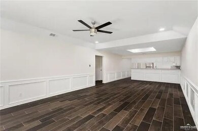 Spare room with ceiling fan, dark wood-style flooring, a decorative wall, and wainscoting