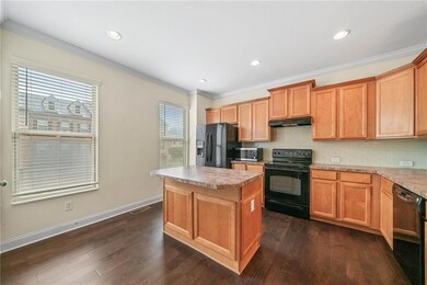 Kitchen featuring black appliances, under cabinet range hood, tasteful backsplash, a kitchen island, and dark wood-type flooring