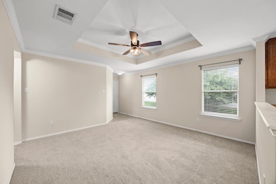 Empty room featuring a tray ceiling, ceiling fan,