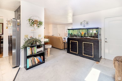 Kitchen featuring freestanding refrigerator, a textured ceiling, and light carpet