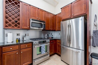 Kitchen with microwave, refrigerator, gas range oven, dark countertops, brown cabinets, and light flooring