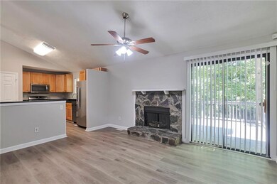 Unfurnished living room with a ceiling fan, light wood-style flooring, lofted ceiling, and a fireplace