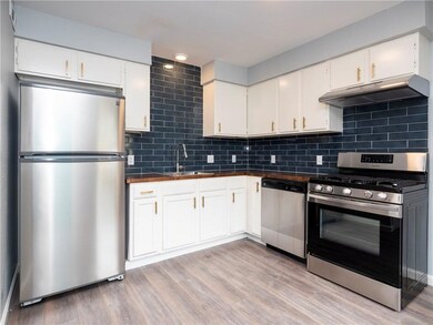 Kitchen with appliances with stainless steel finishes, under cabinet range hood, backsplash, and white cabinets