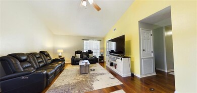 Living area featuring lofted ceiling, ceiling fan, and dark wood-style flooring