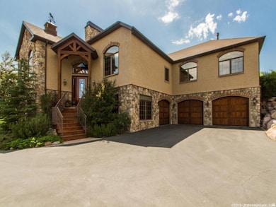 View of front of property with stone siding, stucco siding, driveway, a chimney, and an attached garage