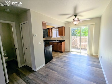Dining area off of kitchen featuring dark countertops, ceiling fan, light wood-style flooring, and brown cabinets