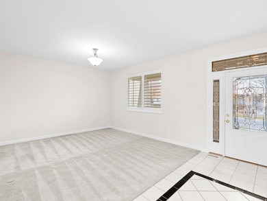 Foyer entrance featuring light tile patterned floors, inlaid floor details, and light carpet