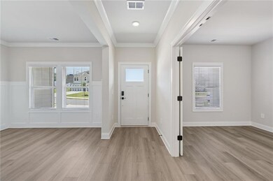 Entrance foyer with light wood-type flooring, crown molding, and wainscoting