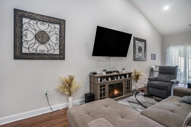Living area featuring baseboards, wood finished floors, high vaulted ceiling, and a glass covered fireplace
