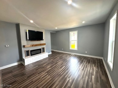 Unfurnished living room with a fireplace, dark wood-style floors, and recessed lighting