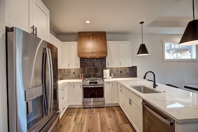 Kitchen featuring stainless steel appliances, a peninsula, white cabinetry, and recessed lighting
