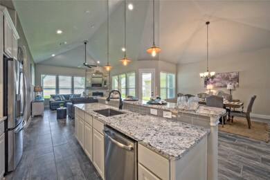 Island Kitchen offers lots of space for the family to be in the kitchen with a generous breakfast bar.  Notice the high ceilings with recessed lighting and pendant lighting. Love the under cabinet lighting too!