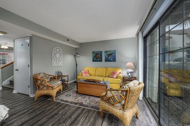 Living area with visible vents, a textured ceiling, wood finished floors, stairway, and baseboards