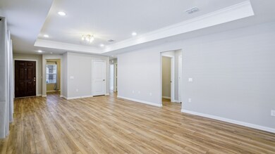 Unfurnished room with a raised ceiling, ornamental molding, recessed lighting, and light wood-style flooring