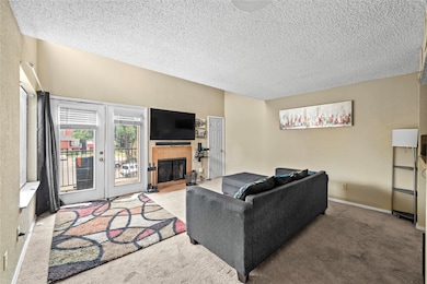 Living area featuring carpet flooring, a tiled fireplace, and a textured ceiling