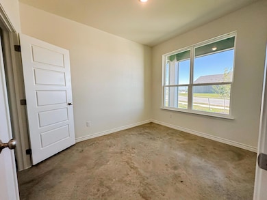 Empty room featuring baseboards and concrete flooring