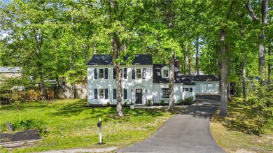 Colonial house with driveway, a chimney, fence, a