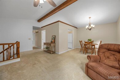 Living area featuring light colored carpet, a chandelier, and a ceiling fan